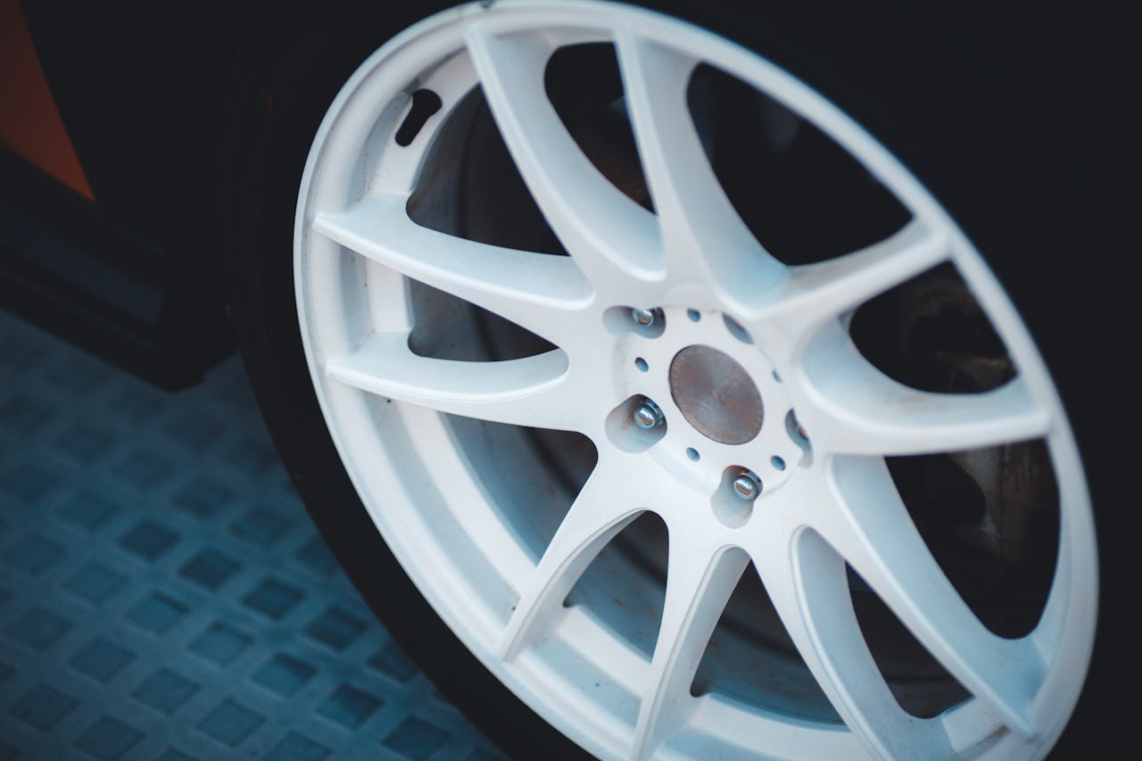 Detailed close-up of a white alloy car wheel showcasing design and craftsmanship.