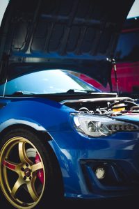 Vertical shot of a blue sports car with open hood showcasing engine details.