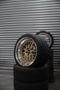 Vertical stack of tires with shiny alloy wheel against a garage wall.