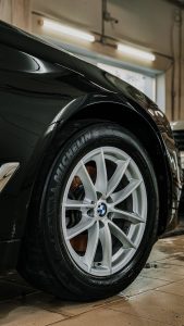 Detailed view of a luxury car wheel in a garage setting, highlighting tire and rim design.