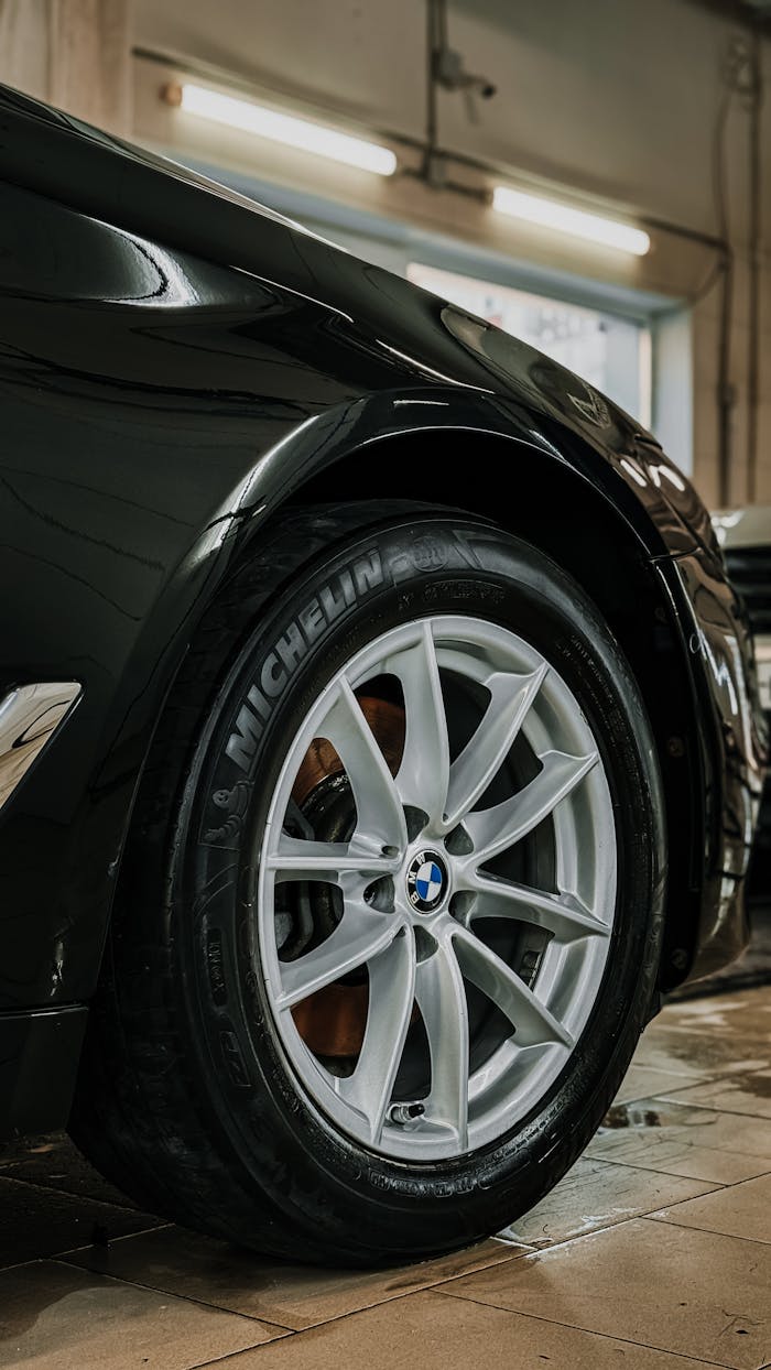 Detailed view of a luxury car wheel in a garage setting, highlighting tire and rim design.