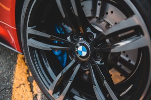 From above modern red auto wheel metal rim with shiny lug nuts on asphalt road with marking line